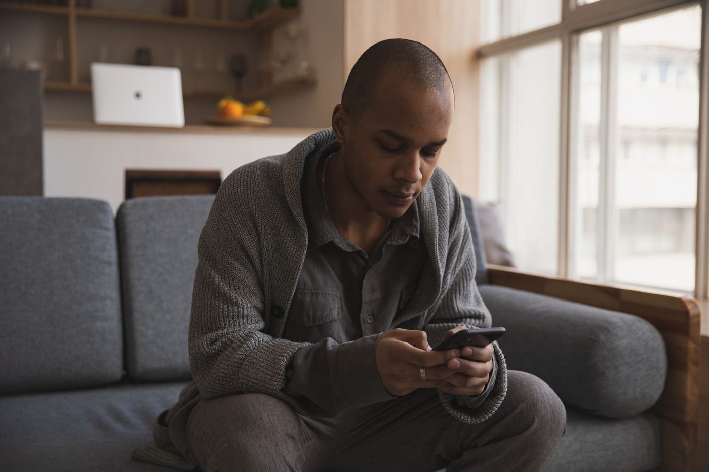 A man sitting on a sofa reading something on his phone