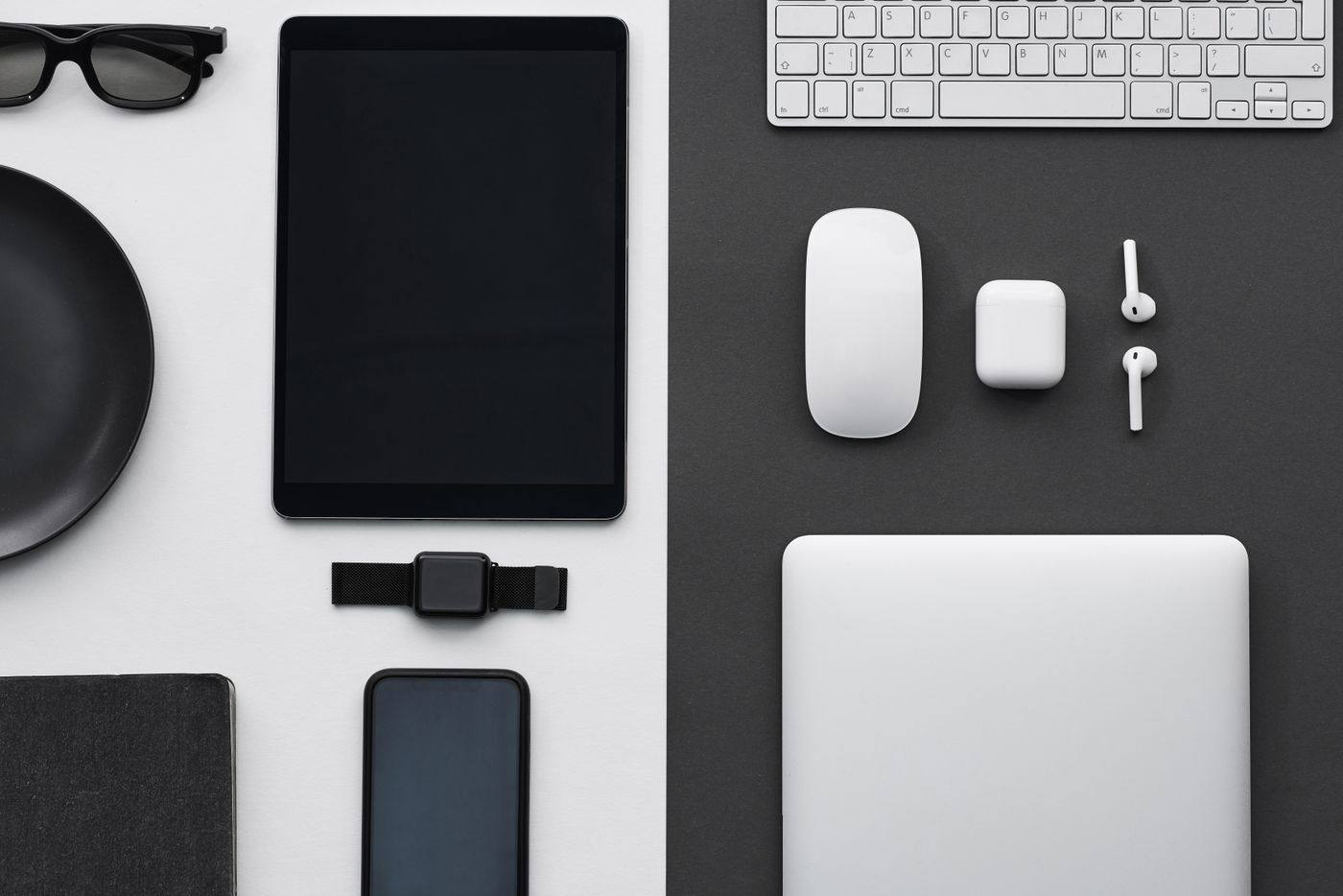 A flat lay of phones and devices on a dark desk