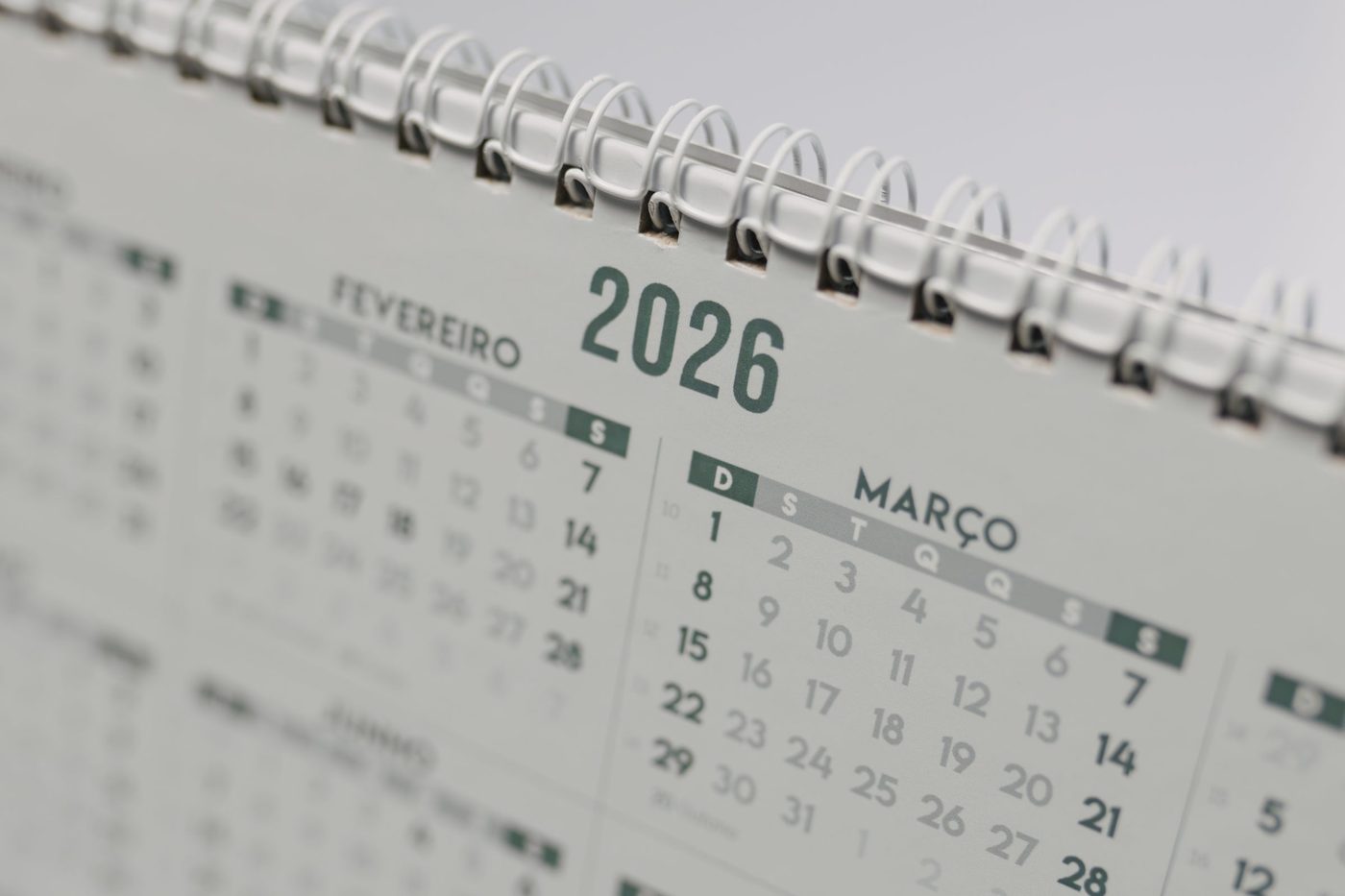 A spiral-bound desk calendar for 2026 in soft focus, showing February and March