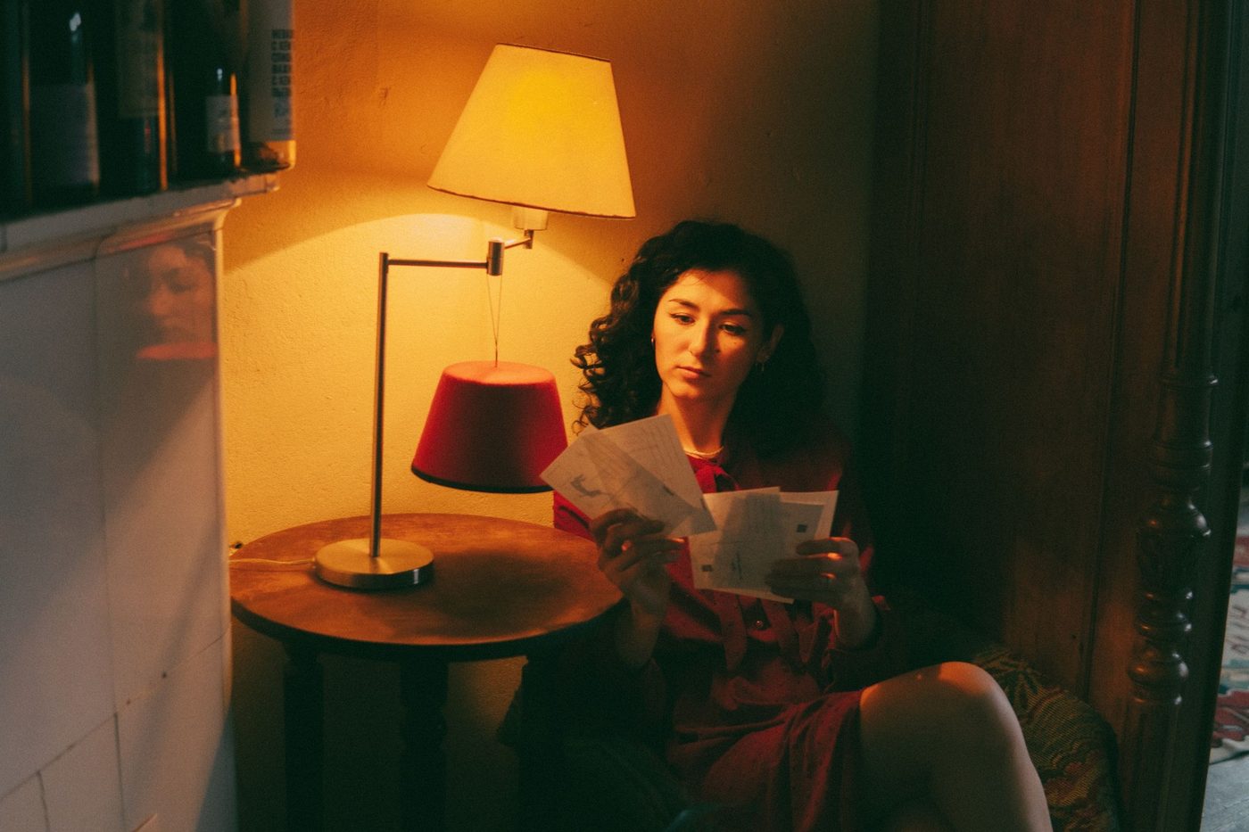 A woman reading letters by the light of a table lamp
