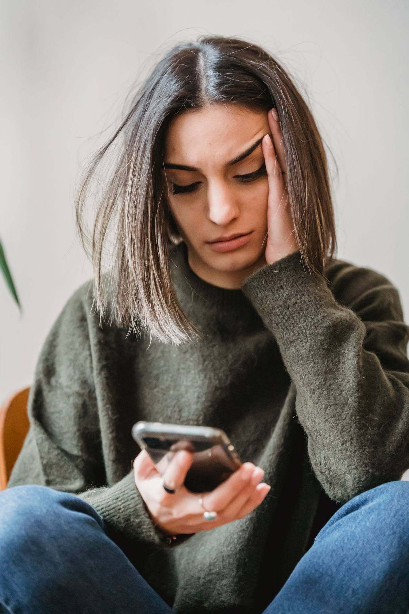 A woman staring at her phone, worried