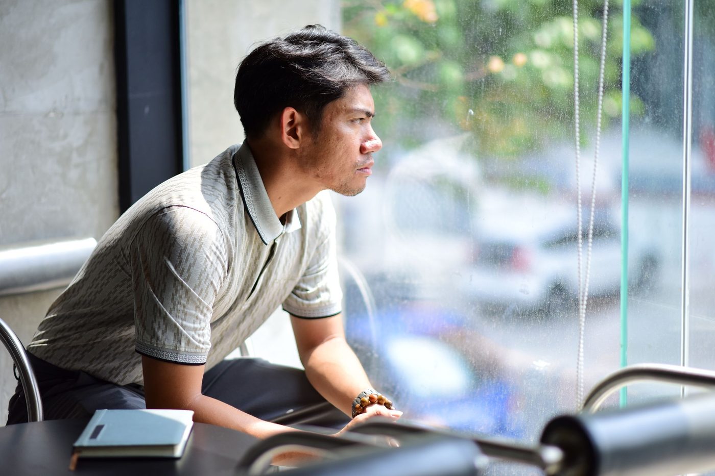 A man leaning on a cafe counter, looking out of the window