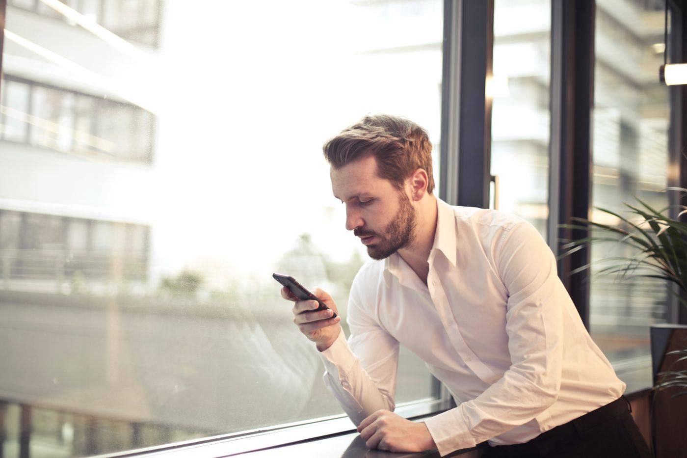 A man reading his phone by a bright window