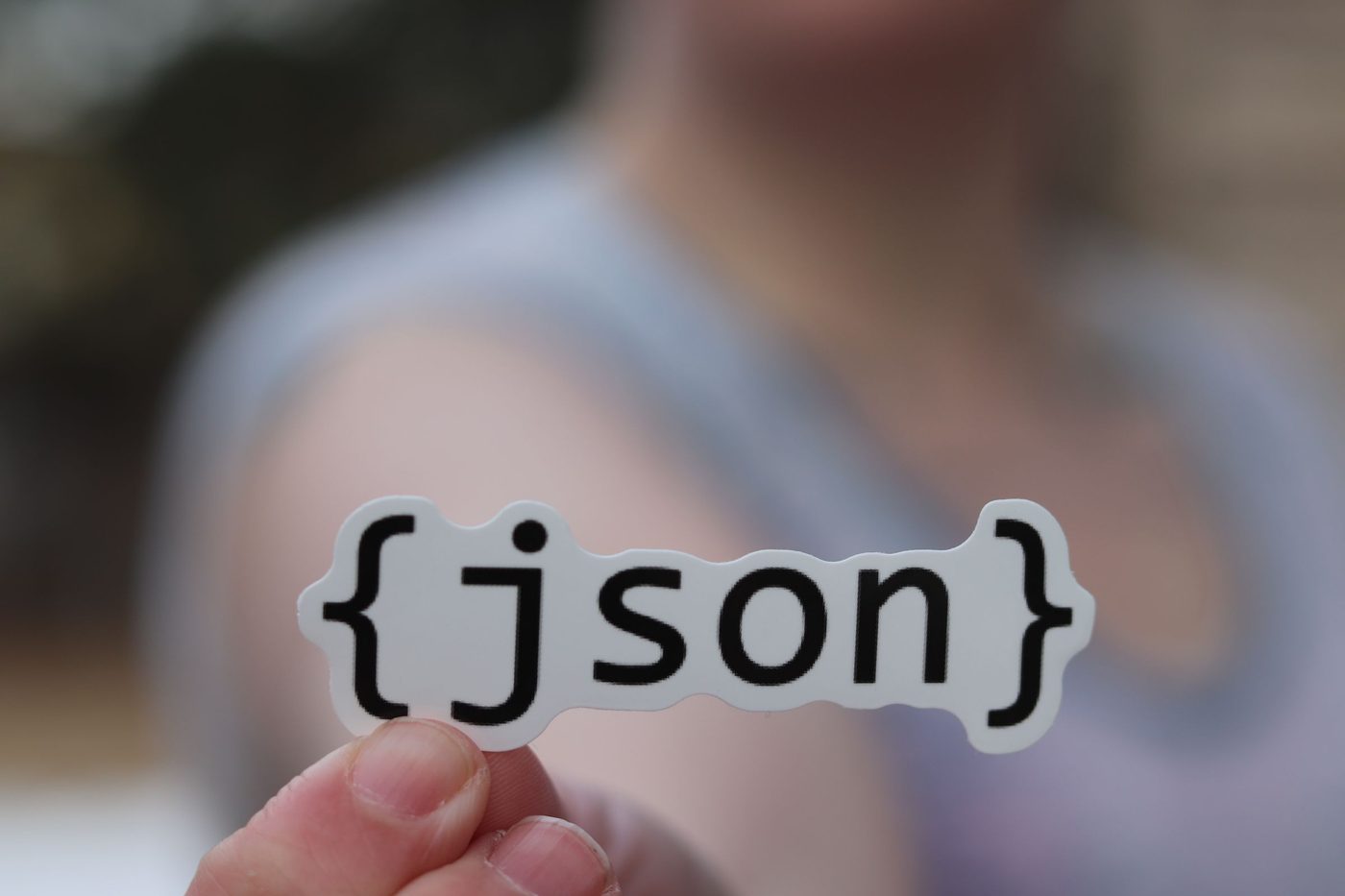 A hand holding a sticker reading json