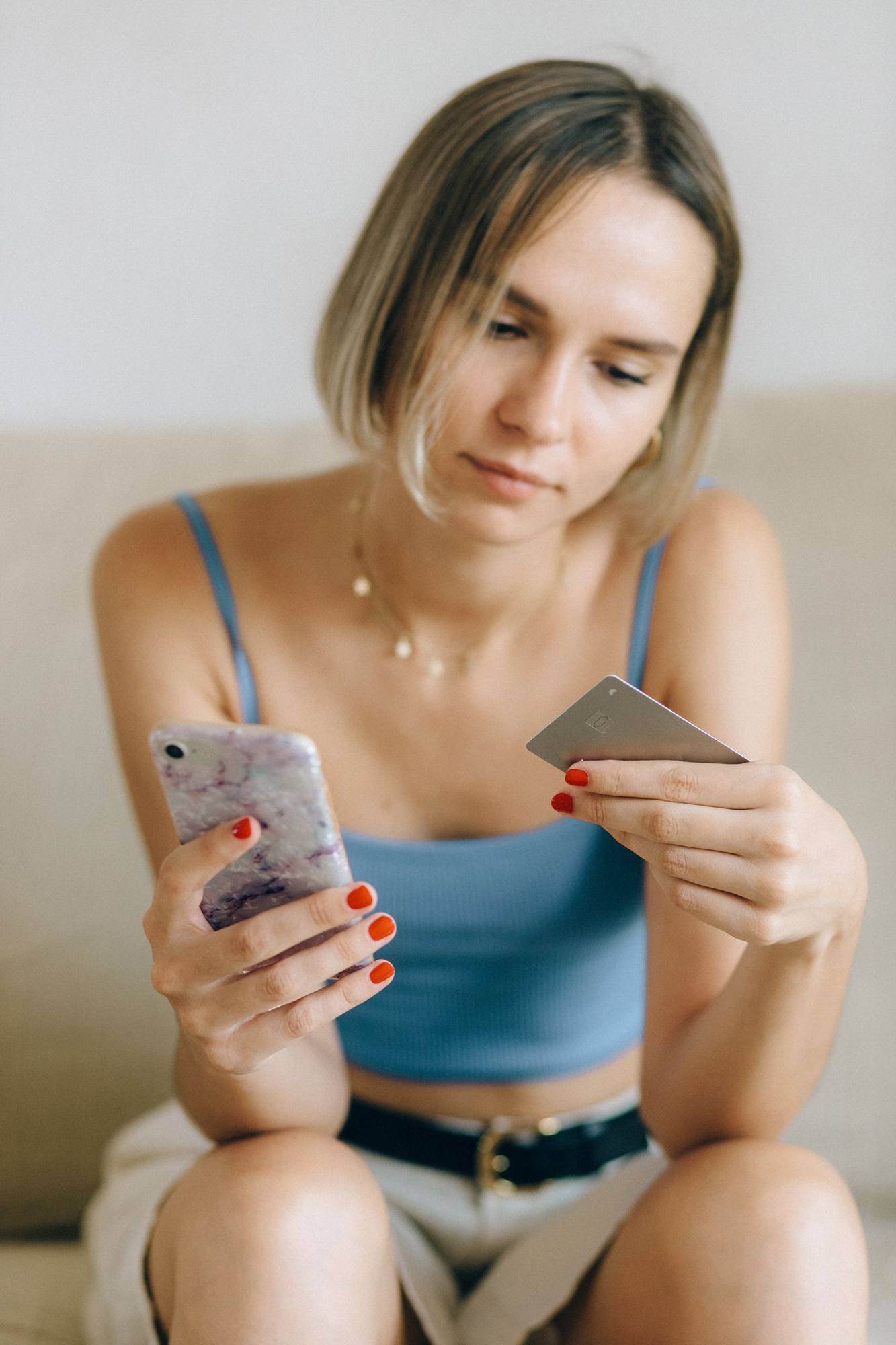 A woman holding her phone and bank card