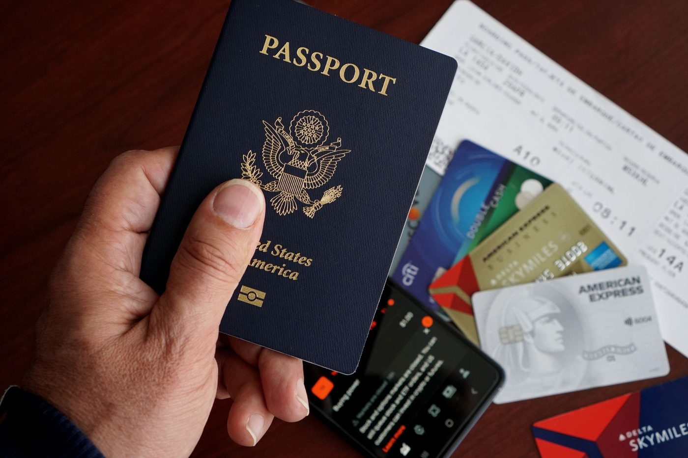 A passport held above bank cards and tickets