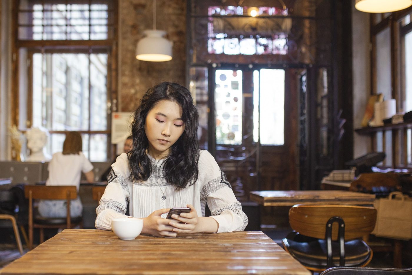 A woman at a cafe table looking at her phone