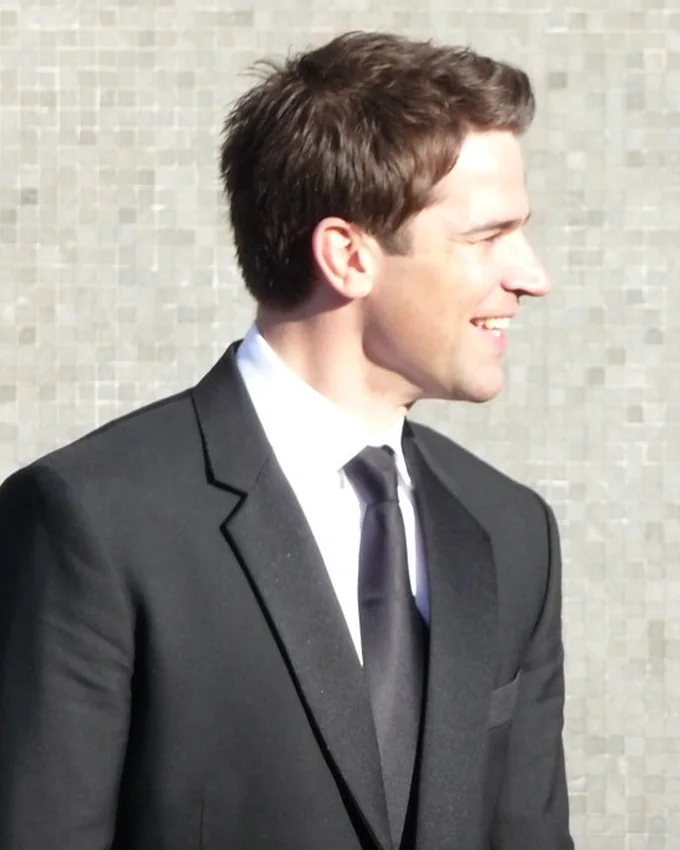 Gethin Jones smiling in a dark suit and tie on the BAFTAs red carpet