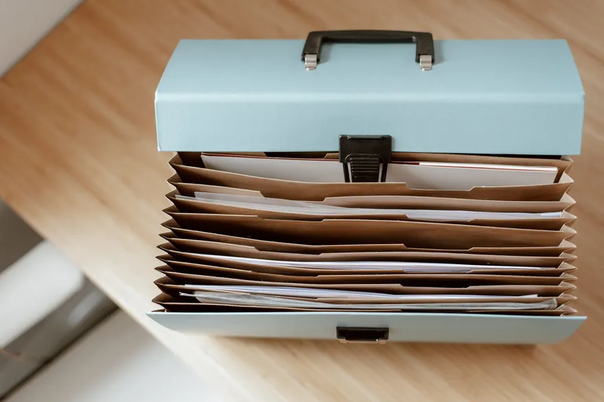 A pale blue document box holding filed folders on a wooden desk